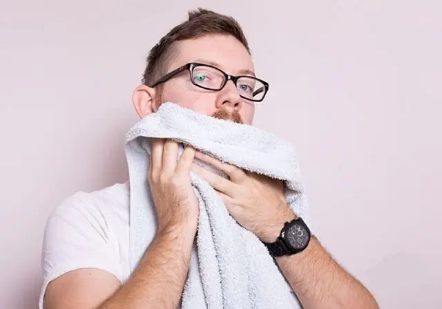 Mand tørrer sit ansigt med et håndklæde