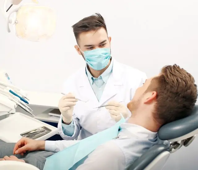Mężczyzna na wizycie u dentysty z powodu brodawczaków pod językiem